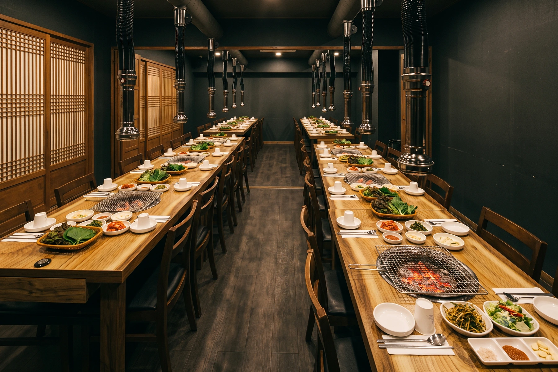 숯불 테이블 위에 찌개와 반찬이 가득 차려진 단체 상차림